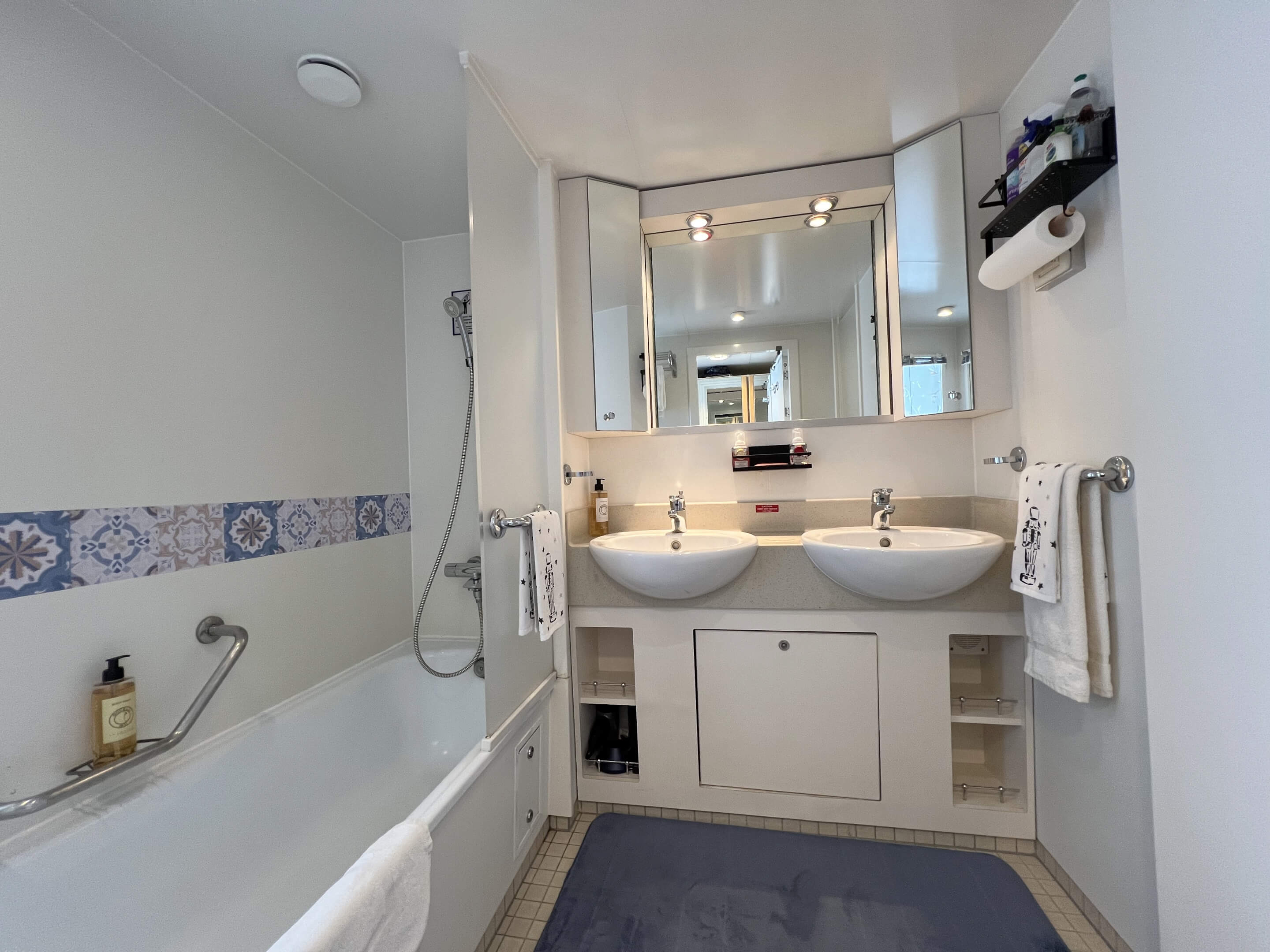 Bathroom with shower over a bath and twin basins